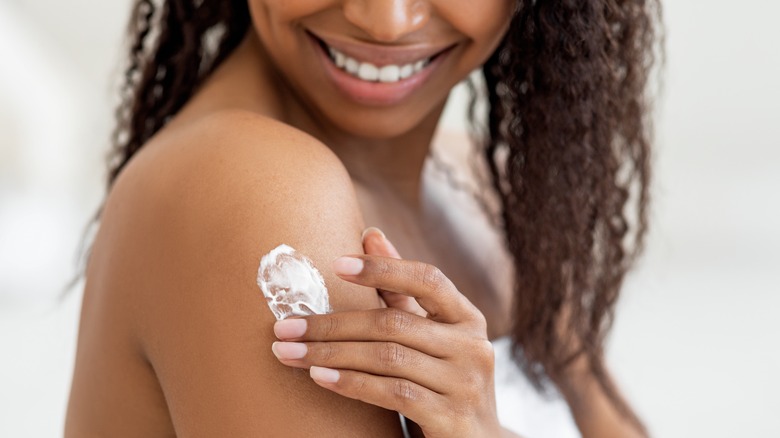 woman putting lotion on arm