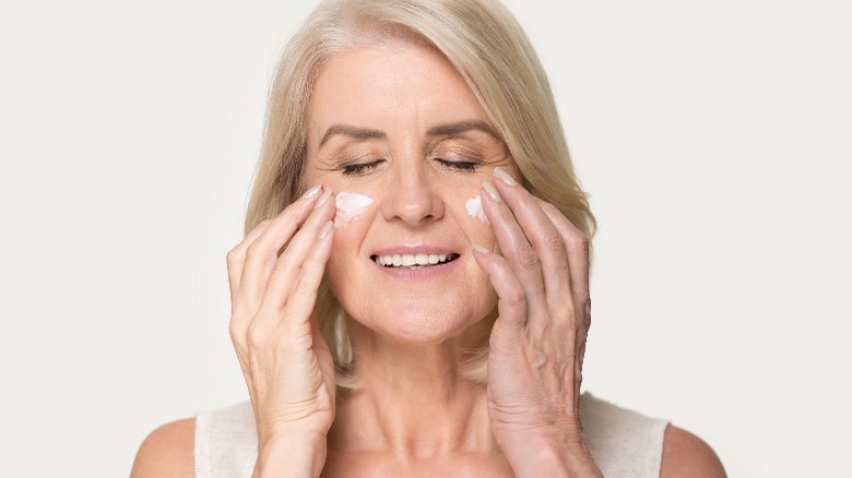 woman applying moisturizer to face