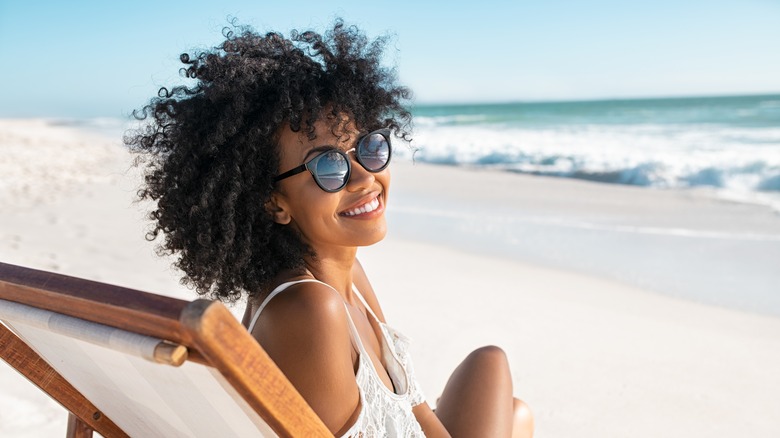 Woman on deck chair beach sunglasses smiling