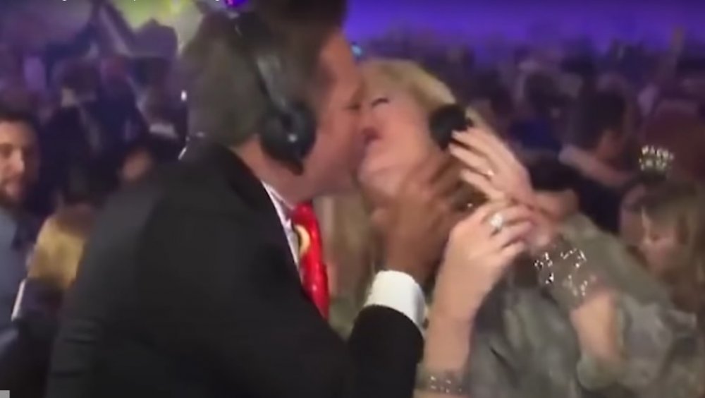 A male anchor kissing a female news anchor on live TV