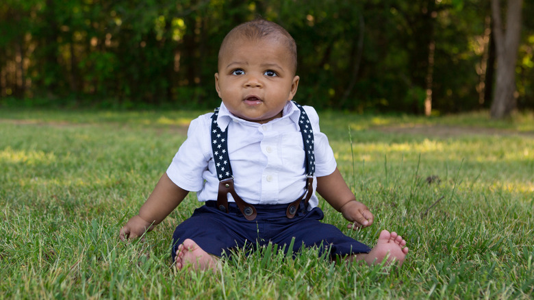 cute kid in suspenders on grass