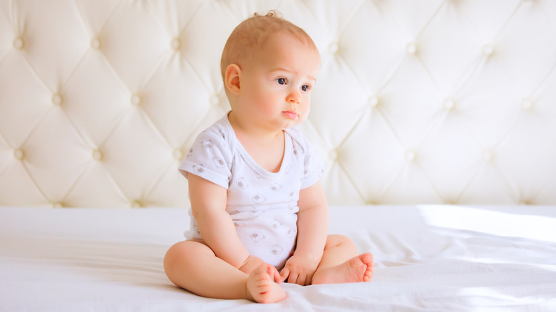 serene baby sitting on bed