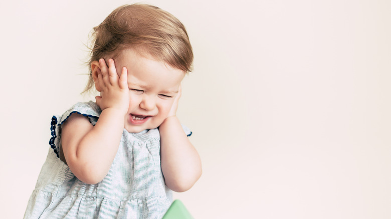 baby with hands on face as if saying oh no