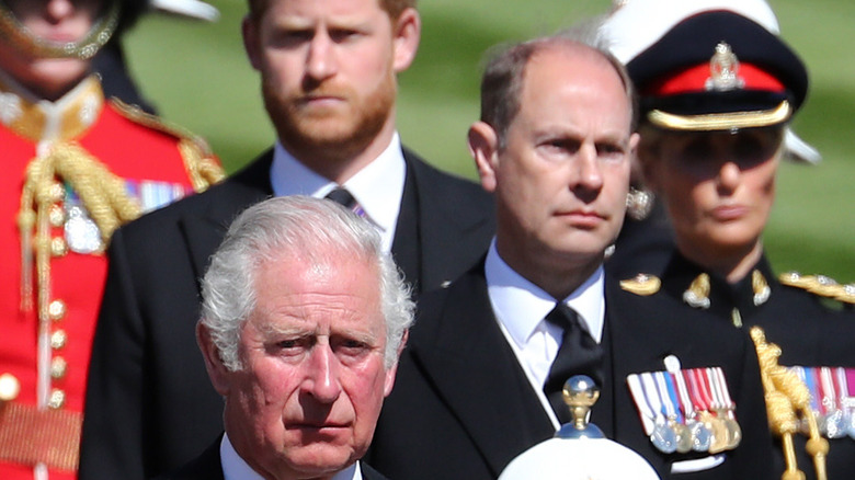 Prince Harry walks behind Prince Charles 