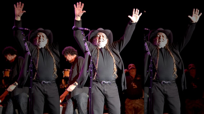 Willie Nelson on stage with his arms held high