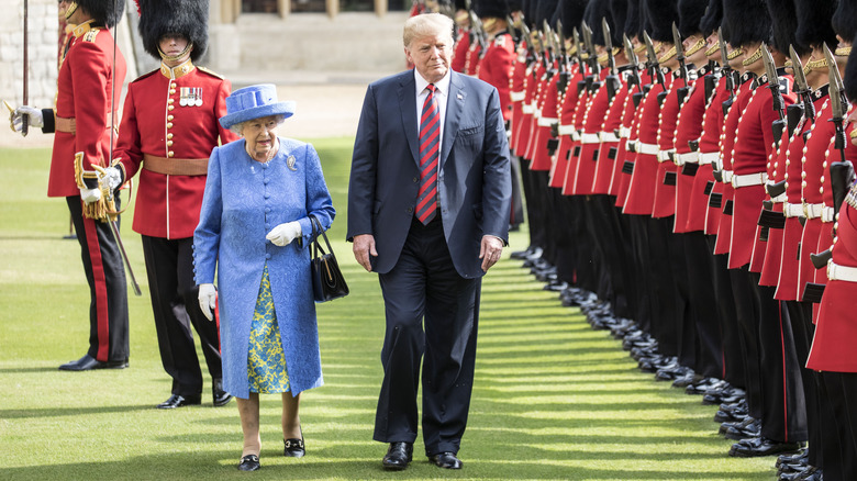 Queen Elizabeth II walking behind Donald Trump