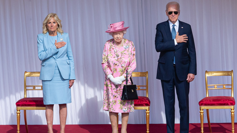 Queen Elizabeth II standing between Jill and Joe Biden