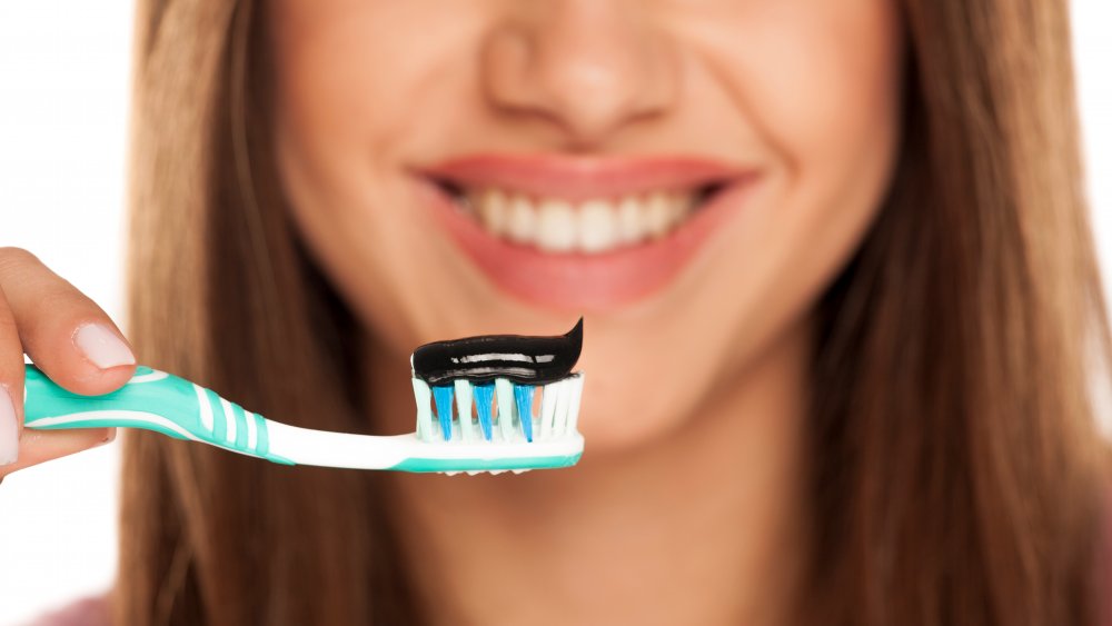 woman brushing teeth with charcoal toothpaste