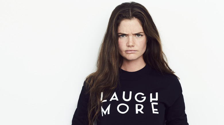 frowning woman wearing shirt with slogan laugh more