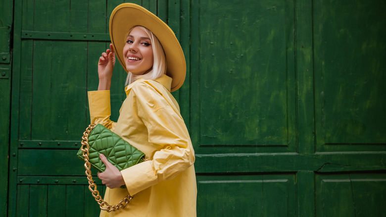 Woman wearing yellow and holding a green bag