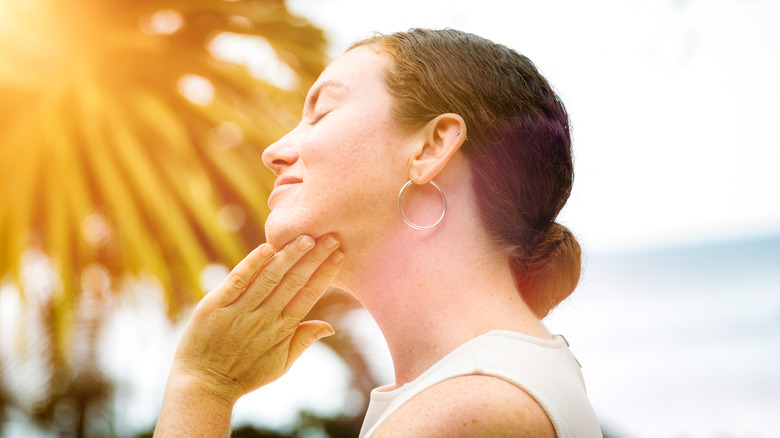 Woman applying face lotion outdoors