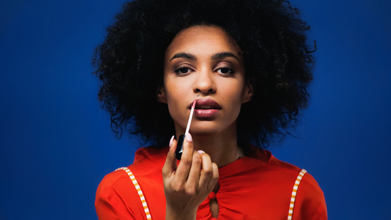 A woman applying lip gloss