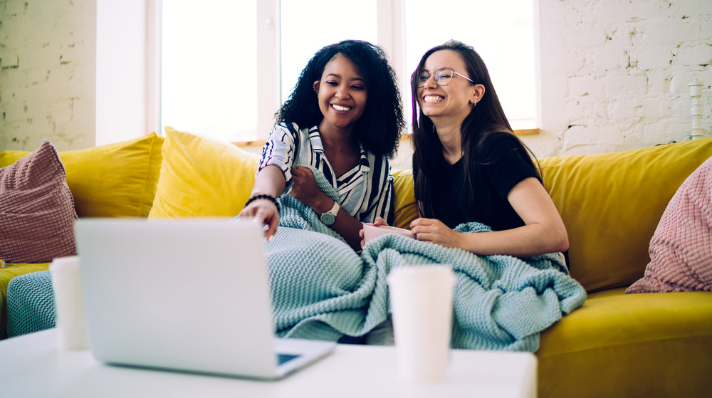 Women sharing a blanket on a couch 