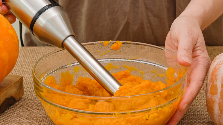 Woman using an immersion blender to make pumpkin puree