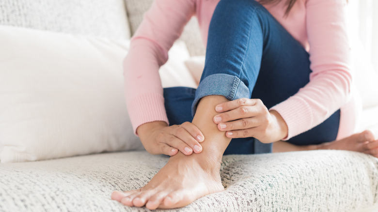 Person in blue jeans rubbing ankle