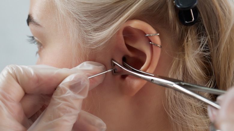 Woman gets her ear pierced with needle