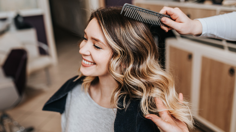 Woman getting balayage hair groomed