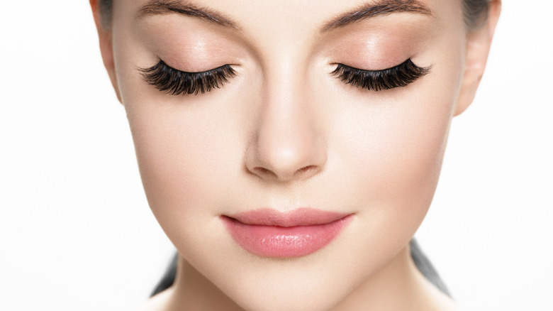 Woman with closed eyes showing long fake eyelashes