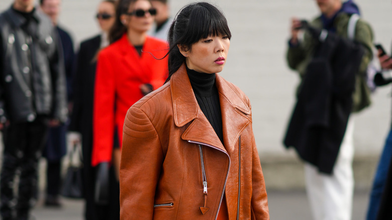 Model wearing black turtleneck and brown leather jacket