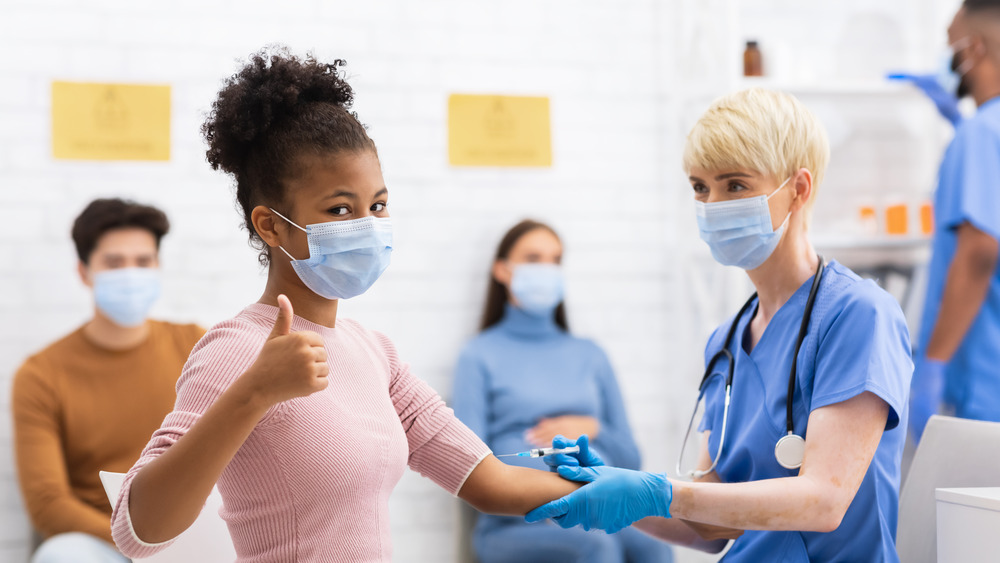 Girl in mask receiving vaccine