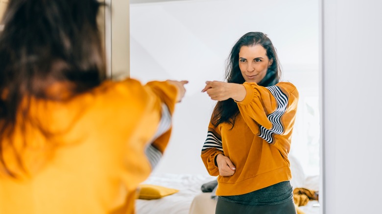Woman points at herself proudly in mirror