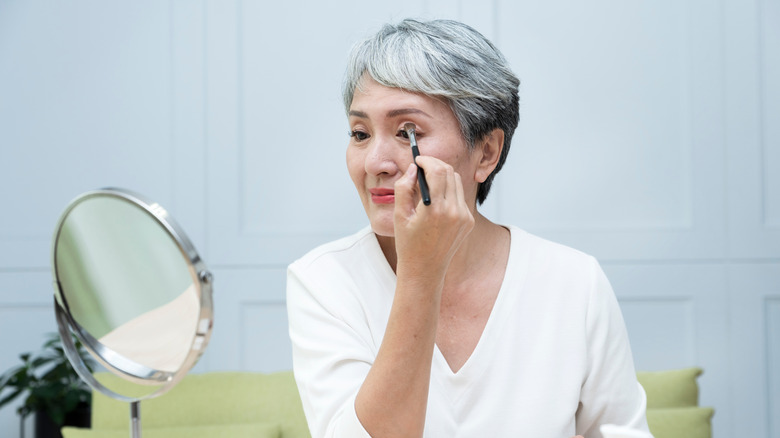 Older woman applying eye makeup