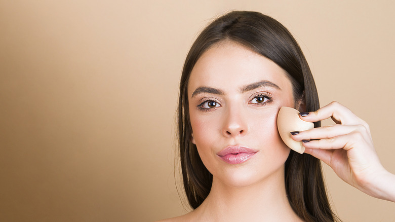 A woman blending concealer on her face