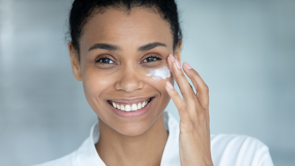 Smiling woman applying facial cream