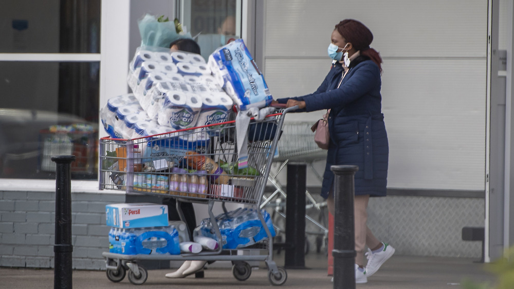 A woman pushing a cartful of Costco products 