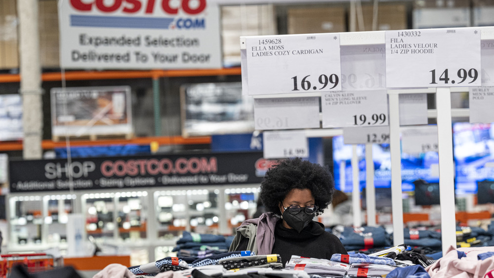 A woman shopping through clothes racks at Costco 