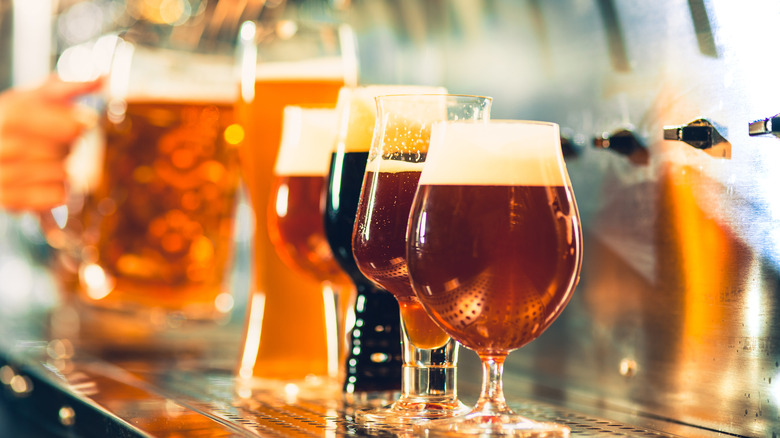 Glasses of beer lined up near taps