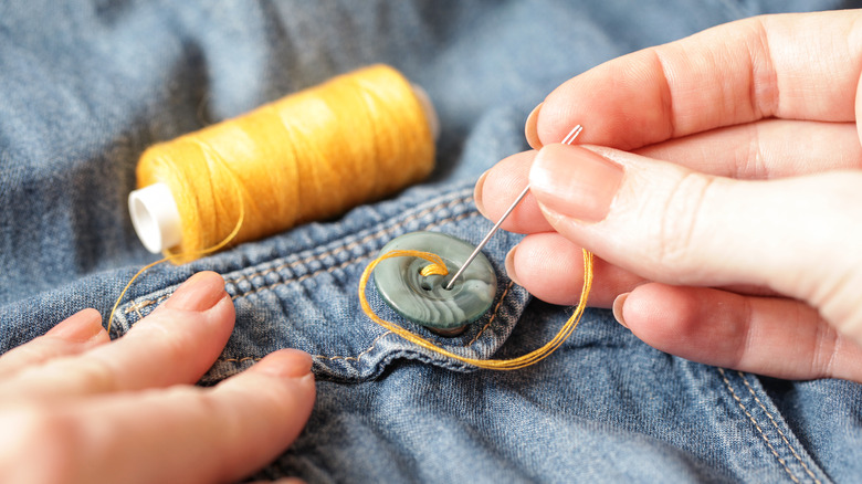 Woman hand sewing a button