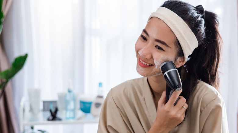 Woman cleaning skin with electronic face brush