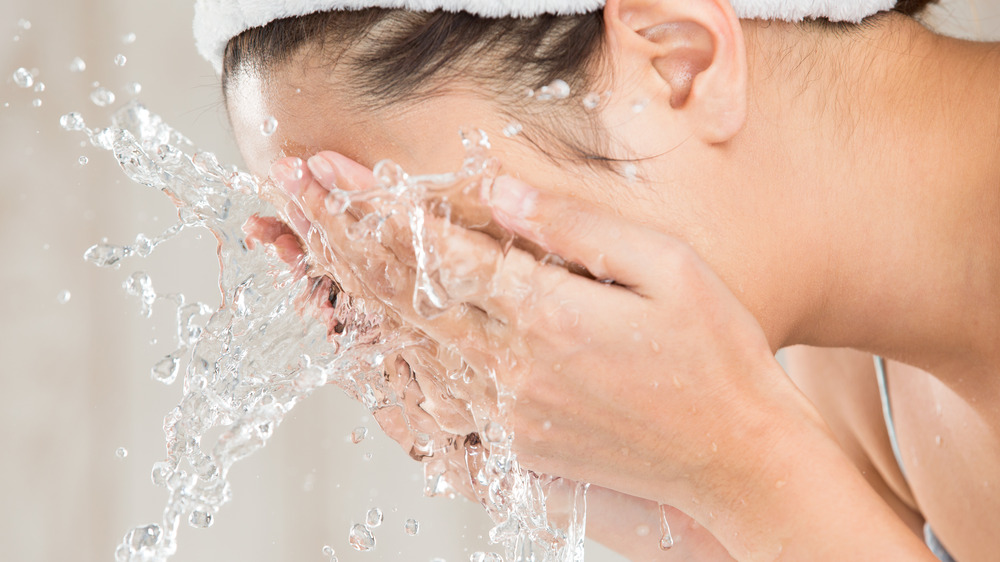 Woman splashing water on her face.