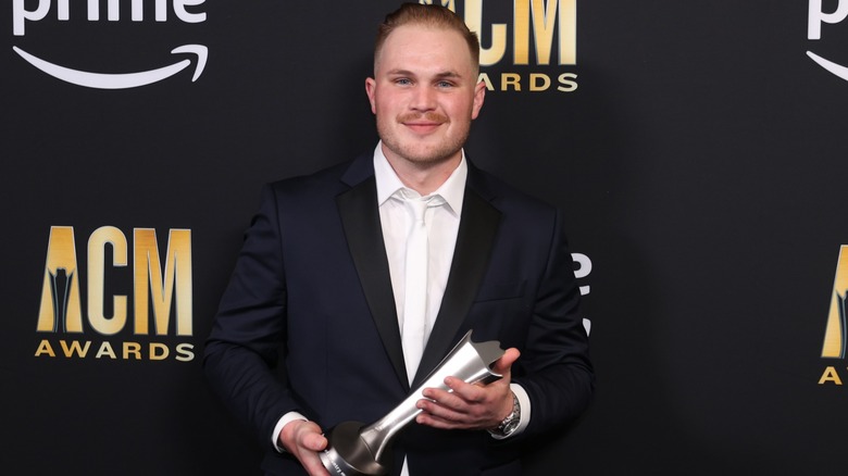 Zach Bryan holding an ACM award