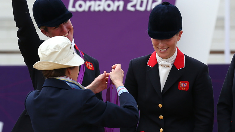 Princess Anne getting ready to put the silver medal on Zara Tindall